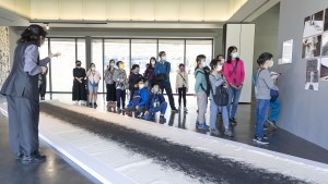 學員聽導覽員解說並欣賞藝術家石晉華「墨行」行動藝術。