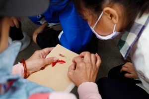 陳老師在拆解珊瑚刺桐花，小朋友凝神緊盯。